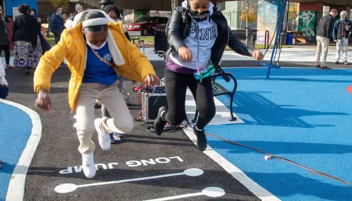 Children and families at East Poplar Playground after its renovation, with the sprayground and play areas part of the site improvements.
