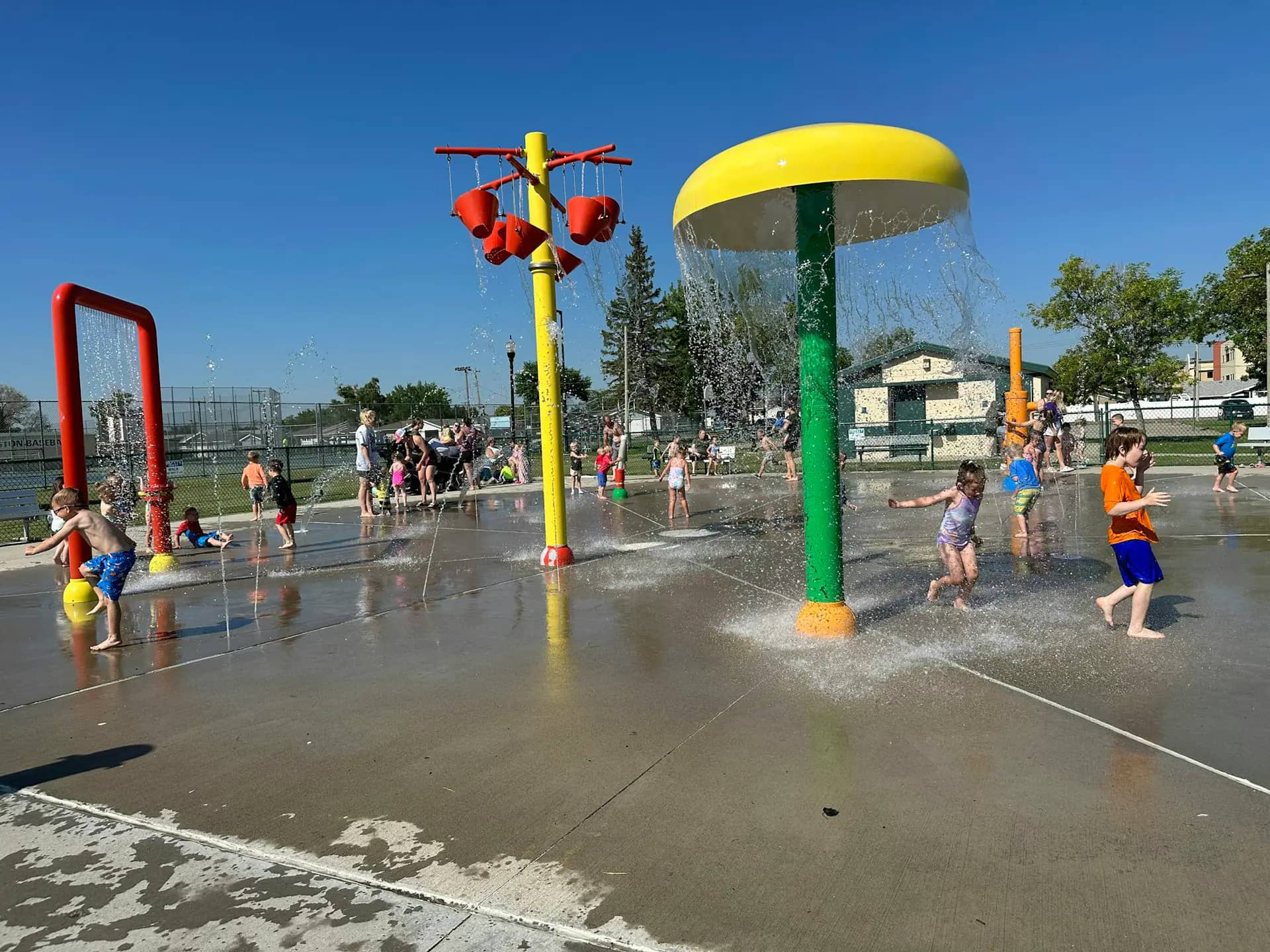 Children playing in the Davidson Park splash pad in Williston on a sunny day.