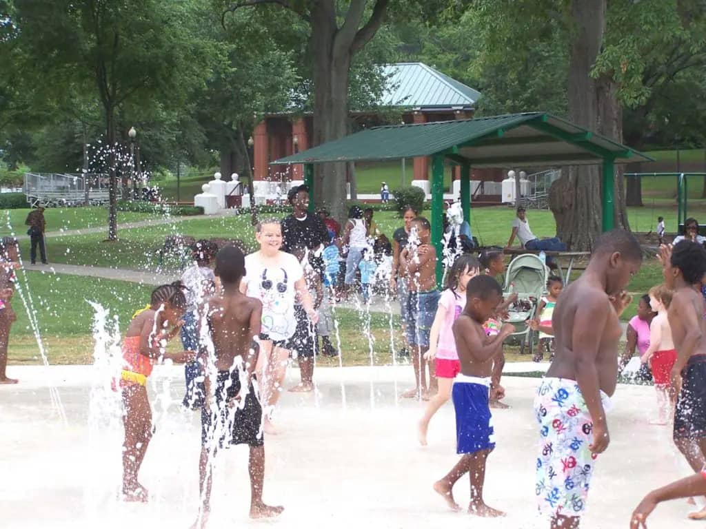 Overview of an Anniston splash pad with children playing in ground sprays.