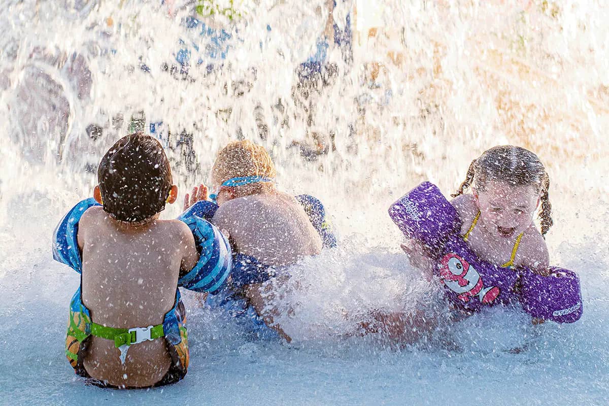 Children splashing in North Liberty water play amenities.