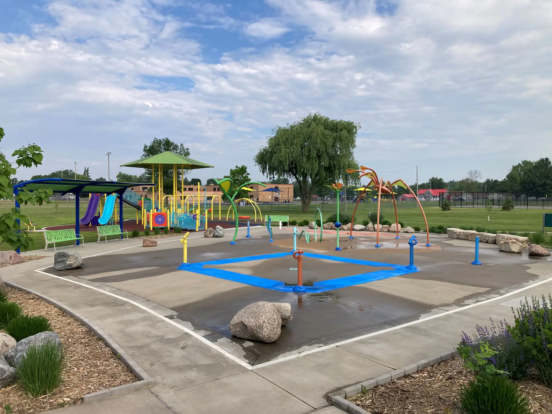 Colorful spray features and seating area at Mead Splash Pad in Wisconsin Rapids.
