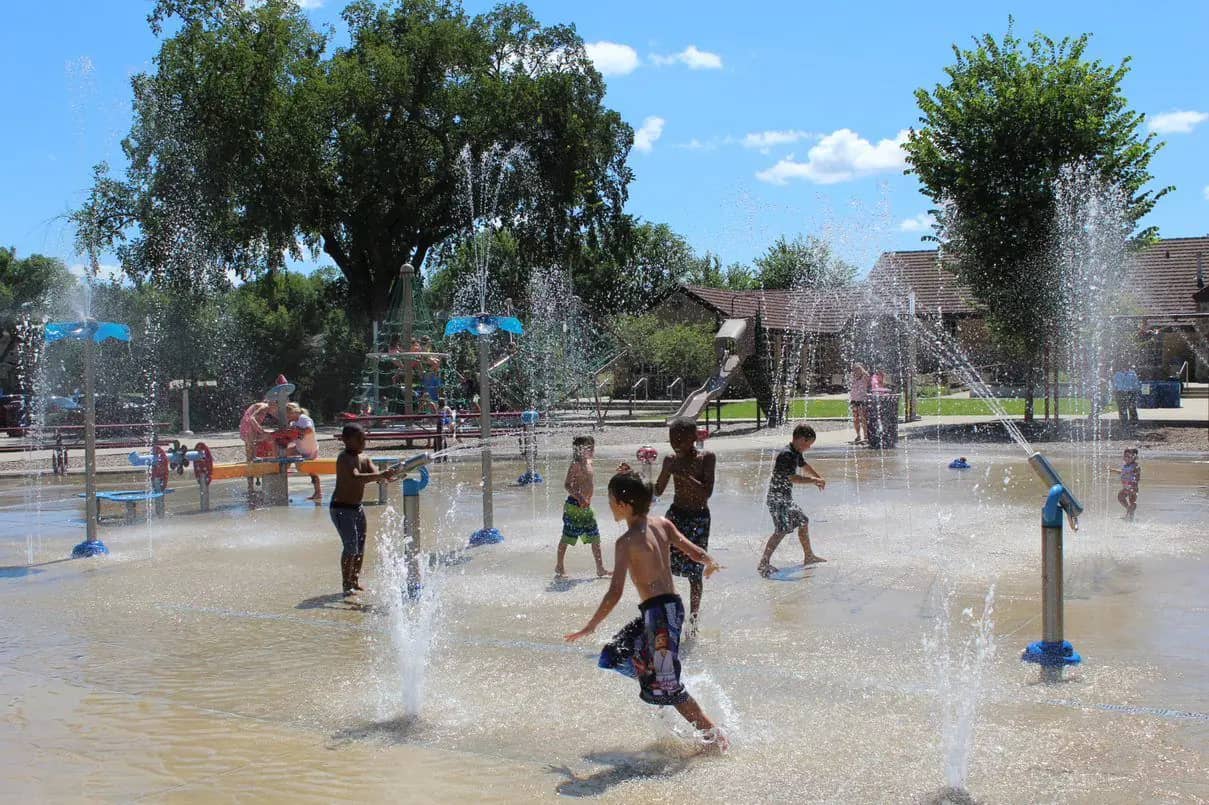 Children running through water spray at a St. Cloud splash pad.