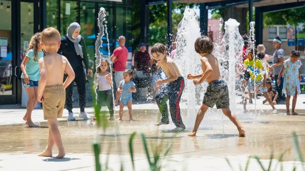 Kids running through the Moore Square water feature in downtown Raleigh.